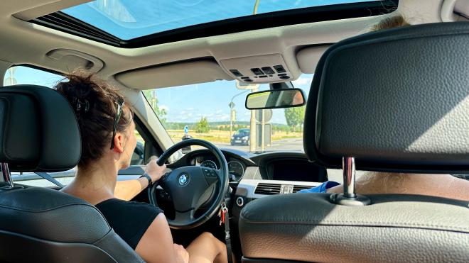 A woman driving a car, seen from the back seat
