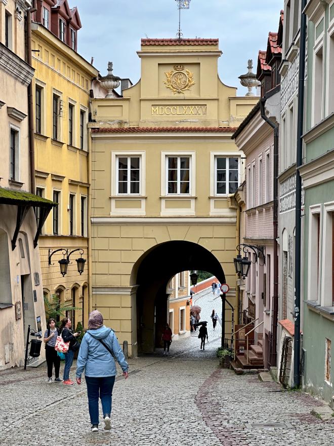 &ldquo;Karen walking down a hill toward an old city gate&rdquo;