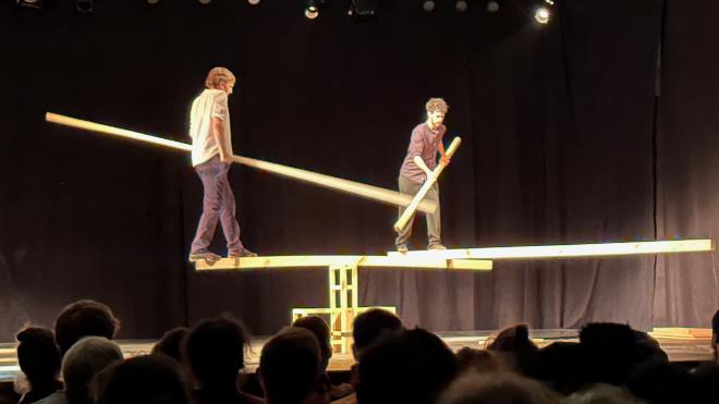 &ldquo;two men on stage balancing on long boards&rdquo;