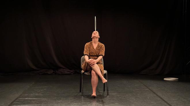 &ldquo;Kathrin Wagner seated on a chair balancing a ring&rdquo;