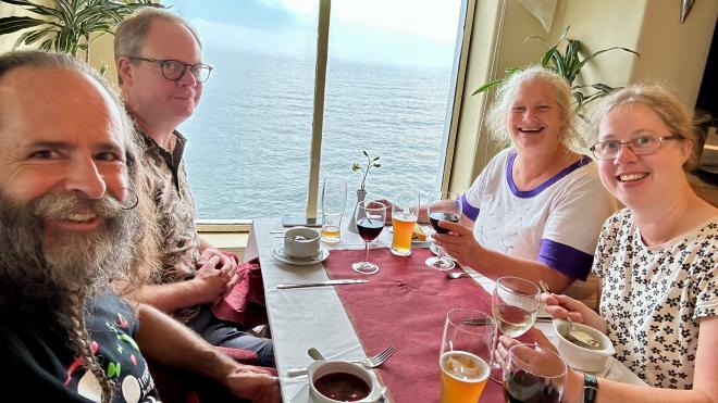 &ldquo;four people around a dining table, with beer and wine, a porthole and open ocean behind them&rdquo;