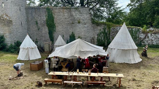 &ldquo;a small medieval camp outside a ruined city wall&rdquo;