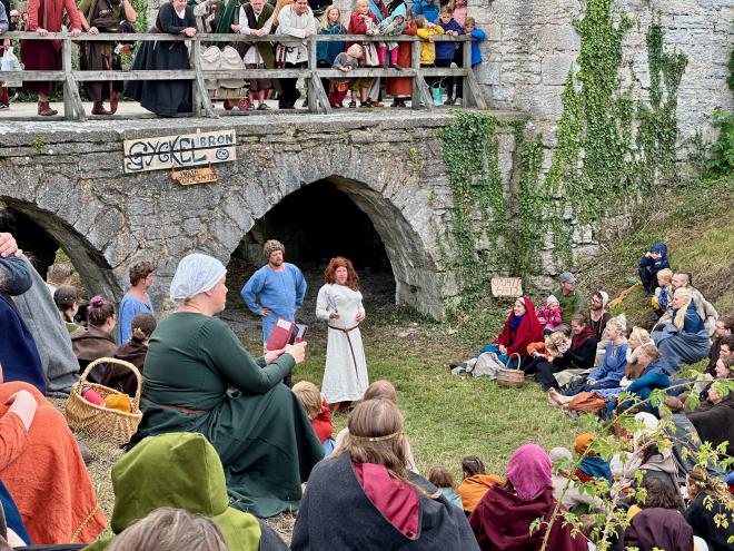 &ldquo;two jesters in a moat, below a bridge, surrounded by spectators in medieval dress&rdquo;