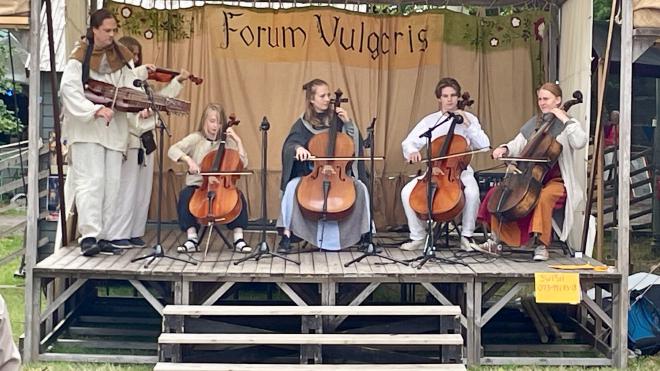 &ldquo;six musicians with string instruments on a small rustic stage&rdquo;