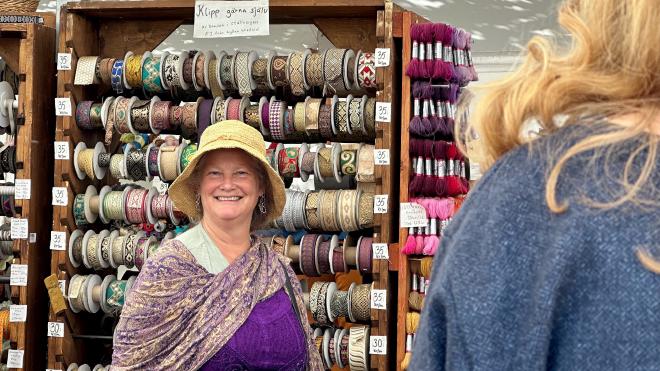 &ldquo;Karen in medieval garb standing in front of a rack of spools of decorative woven ribbon&rdquo;
