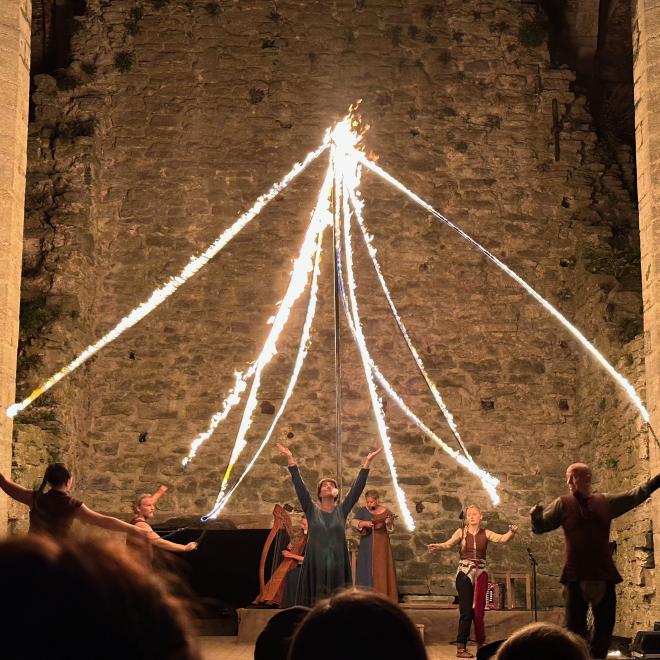 &ldquo;four performers around a maypole-like structure with eight burning ropes attached. there is a singer in the centre, and two musicians behind&rdquo;