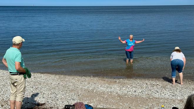 &ldquo;Karen with her trousers rolled up to her knees, standing in the sea. Maria is rolling up her trouser legs. Gunnar looks on.&rdquo;